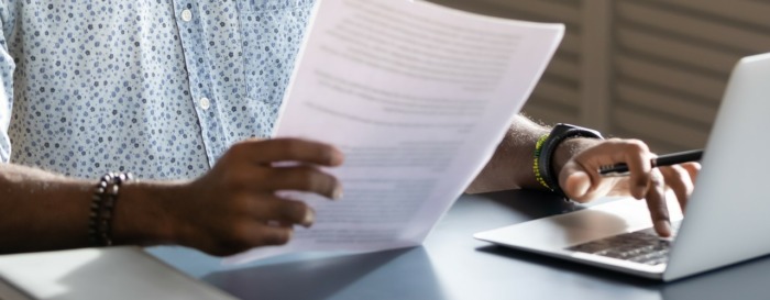 Man working from home with a laptop reading a letter made by letterhead graphic design company