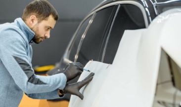 Employee wrapping a car with a vehicle livery