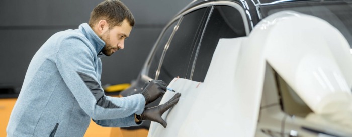 Employee wrapping a car with a vehicle livery