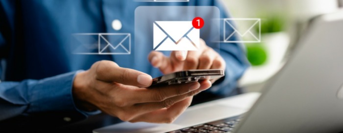 A person types on a smartphone with a laptop nearby, while a digital envelope icon—representing the digital mail room and indicating a new email notification—appears above the device.