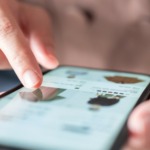 A person uses a smartphone, scrolling through an online shopping app. A finger taps images of clothing, displaying a focused and engaged interaction.
