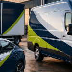 Branded commercial vehicles parked outside a modern industrial building