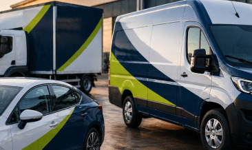 Branded commercial vehicles parked outside a modern industrial building